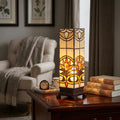 Rectangular Tiffany lamp with intricate stained glass patterns glowing warmly on a dark wooden side table.