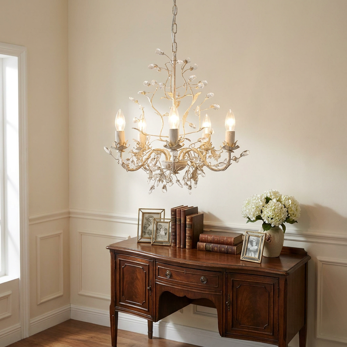 Cream gold Almandite 5-light chandelier with crystal buds hanging above a wooden sideboard with décor.