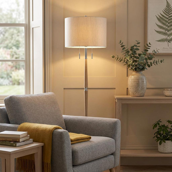 Altesse floor lamp with a wooden stand and oatmeal fabric shade in a warm, cozy living room setting.