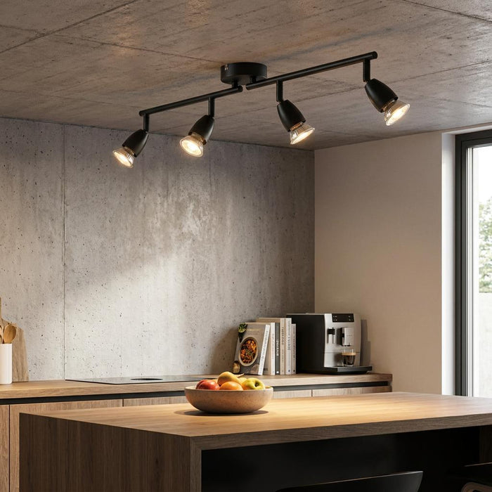 Amalfi 4-light black bar spotlight illuminating a modern kitchen with concrete walls and wooden countertops.