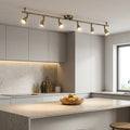 Saxby Amalfi 6-light antique brass spotlight bar illuminating a modern kitchen island with white cabinetry.