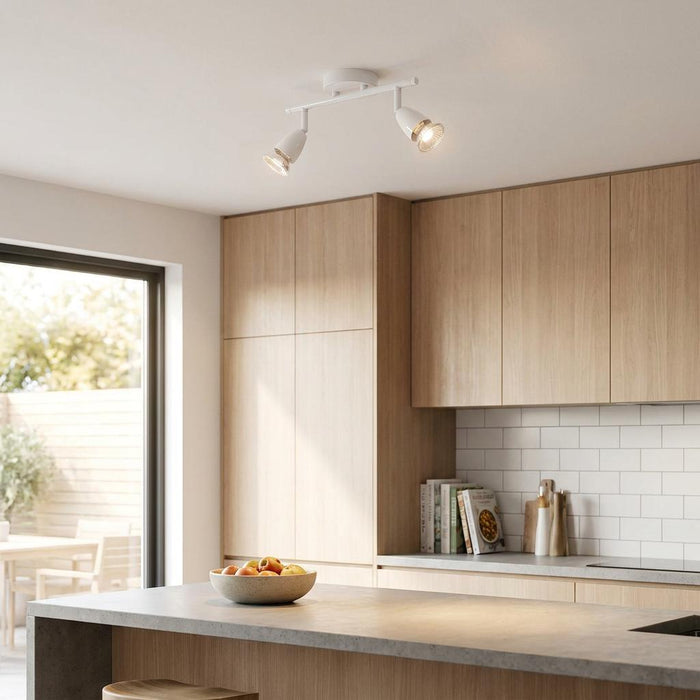 White gloss 2-light spotlight fixture illuminates a modern kitchen with wood cabinets and a stone island.