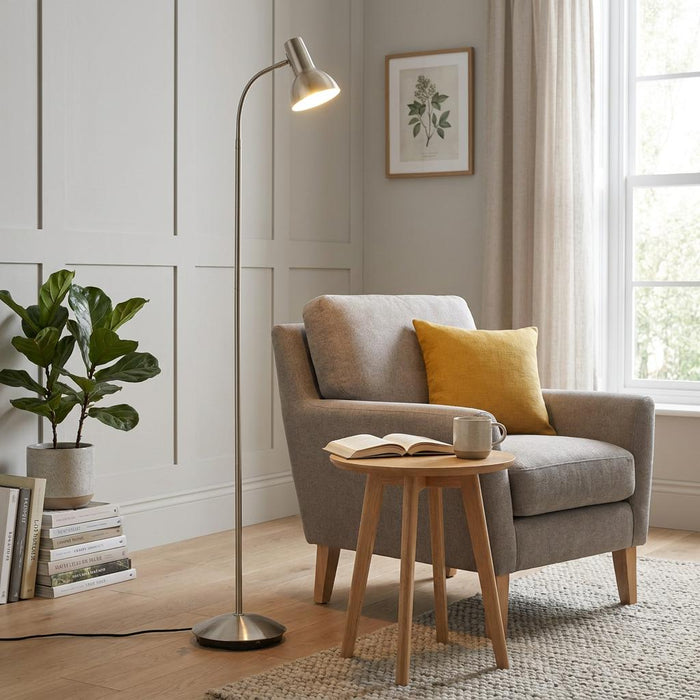 Amalfi Satin Nickel Floor Lamp lighting a grey armchair and wooden side table in a modern living room.