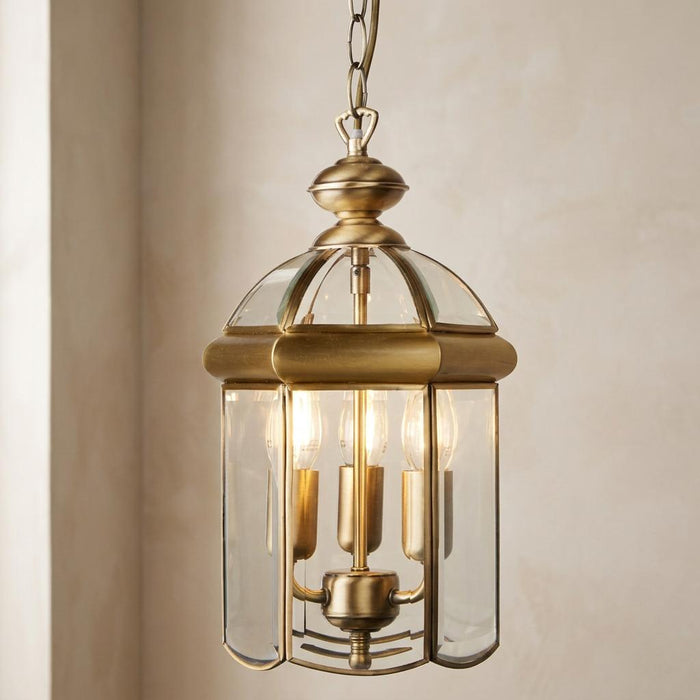 Antique brass domed 3-light lantern ceiling light with curved glass panels hanging from a chain.