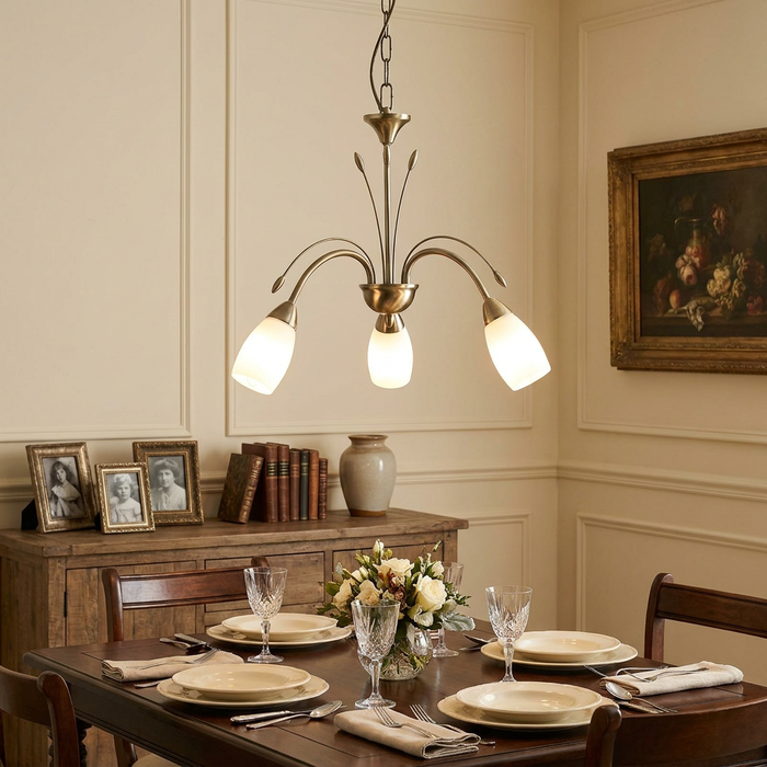 An antique brass 3-light chandelier with frosted white glass shades hanging above a set dining table.