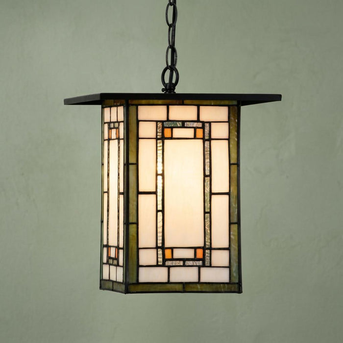 Mission-style Aragon Tiffany ceiling light with geometric stained glass panels and a black chain against a green wall.