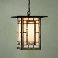 Mission-style Aragon Tiffany ceiling light with geometric stained glass panels and a black chain against a green wall.