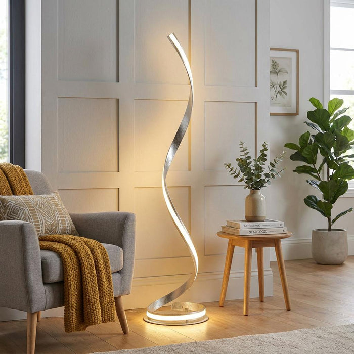 Aria Modern Nickel LED Floor Lamp featuring a spiral ribbon design, illuminated in a cozy living room setting.