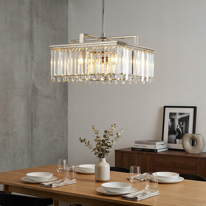 Rectangular polished nickel and crystal chandelier hanging above a modern wooden dining table set for four.