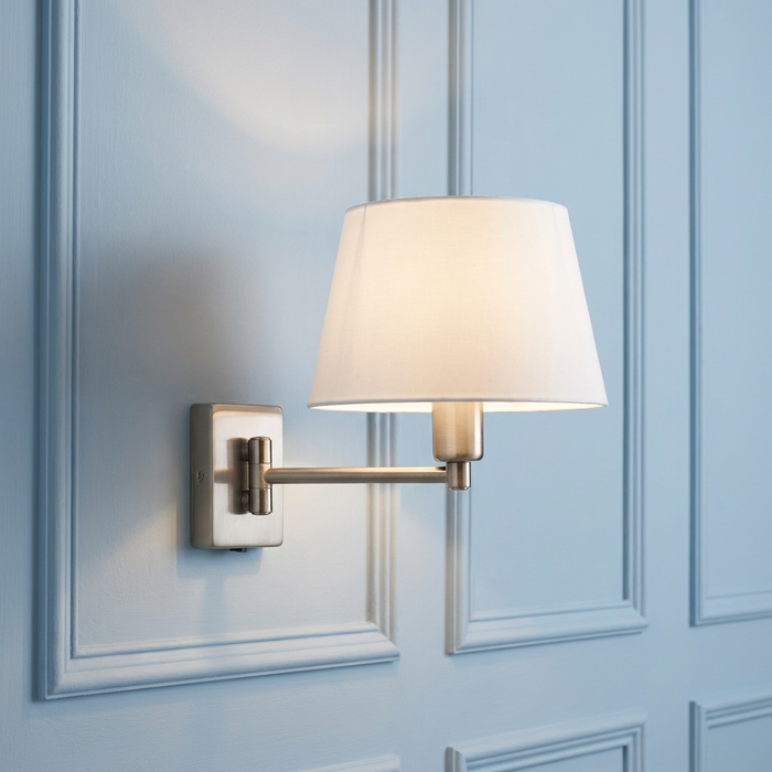 Armada antique chrome single swing arm wall light with a white fabric shade mounted on a blue paneled wall.
