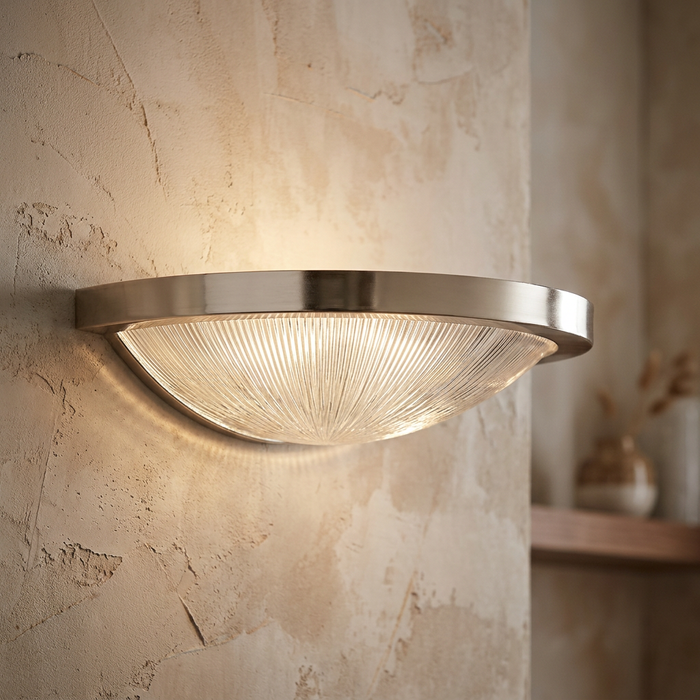 Art Deco wall sconce with a ribbed glass dish and brushed metal rim, mounted on a textured beige wall.