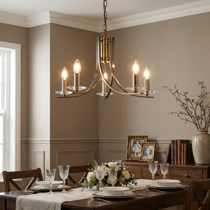 Antique brass 5-light chandelier with glass sconces illuminating a set dining room table.