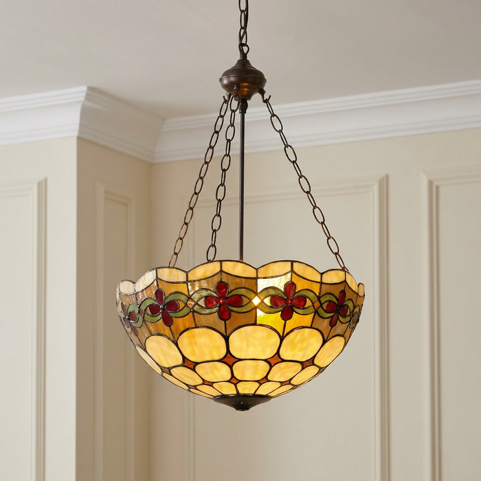 Inverted Tiffany ceiling light with amber stained glass and red floral patterns suspended by bronze chains.