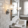 Lit polished chrome wall light with a fluted glass cloche shade on a white subway tile bathroom wall.