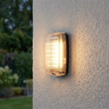 Illuminated Avit 10W outdoor wall light with a ribbed cover mounted on a textured white exterior wall.