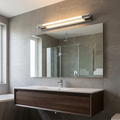Avora Chrome Finish Bathroom Wall Light mounted above a large mirror in a modern grey tiled bathroom.