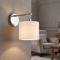 Modern wall sconce with polished nickel finish and white fabric shade illuminating a contemporary living room.
