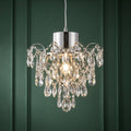 Belle chrome crystal chandelier illuminated against a dark green paneled wall.
