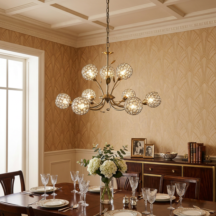 Brass 9-light chandelier with crystal ball shades hanging over a formal dining table in a room with patterned wallpaper.
