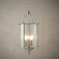 Polished chrome bevelled lantern ceiling pendant with three glowing bulbs against a neutral textured wall.