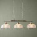 Three-light silver bar pendant with textured holophane glass shades against a green textured wall background.