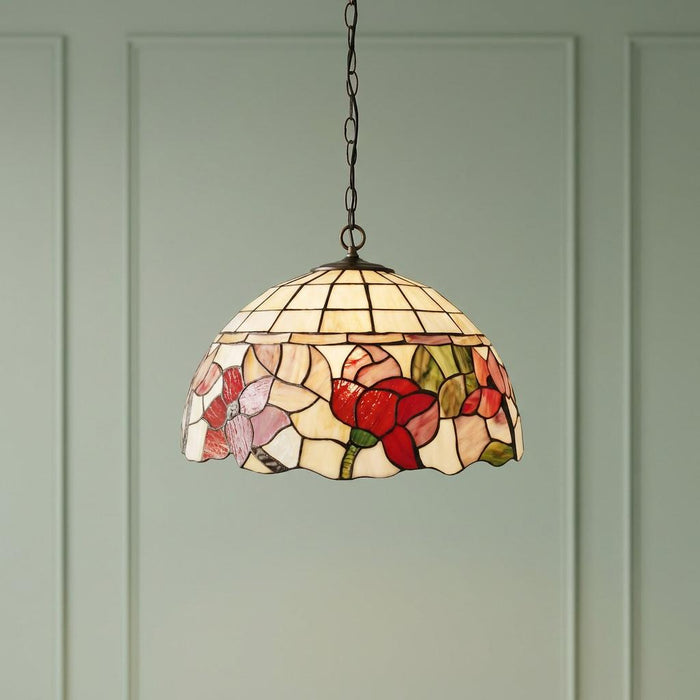 Tiffany-style floral stained glass pendant light hanging against a soft green paneled wall.
