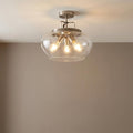 Boule silver semi-flush ceiling light featuring a clear glass bowl shade and three glowing bulbs on a white ceiling.