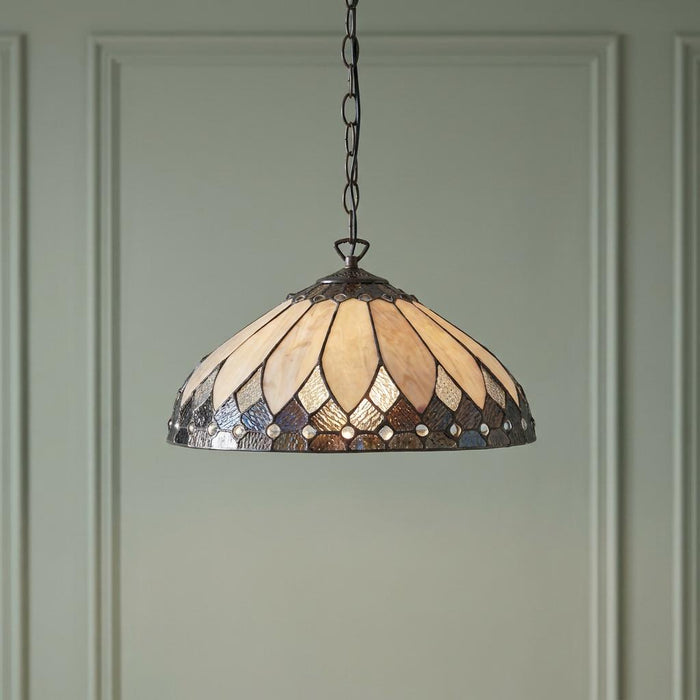 Tiffany-style pendant light with a cream and dark stained glass shade hanging against a pale green paneled wall.