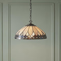 Tiffany-style pendant light with a cream and dark stained glass shade hanging against a pale green paneled wall.