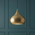 Matt antique brass teardrop pendant light hanging against a dark teal paneled wall.