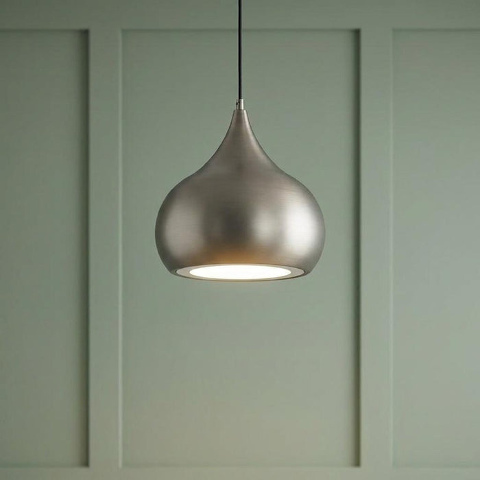 Matt nickel teardrop pendant light glowing against a sage green wood-paneled wall.