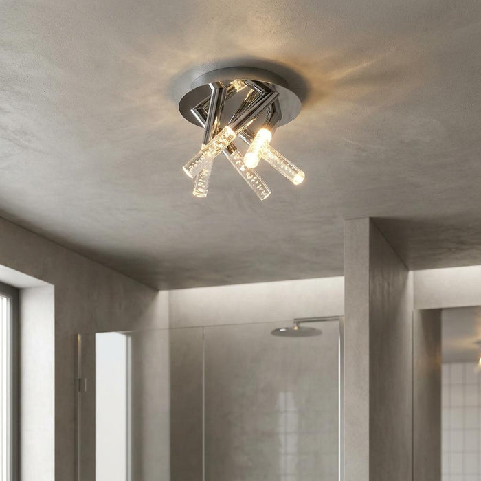 Modern five-light chrome flush ceiling fixture with bubble glass cylinders mounted in a grey bathroom.