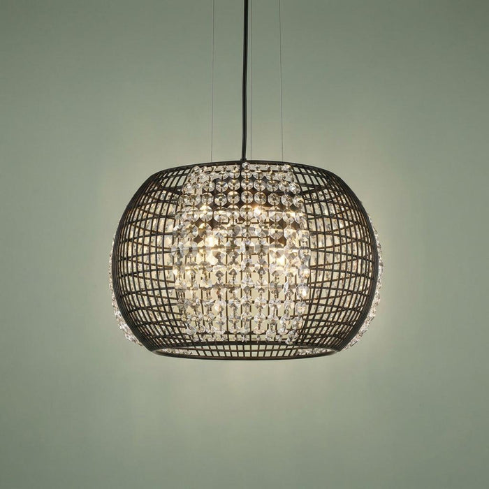 Black wire cage drum pendant light with crystal glass panels and internal bulbs glowing against a light background.