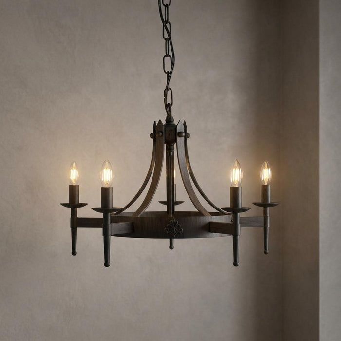 Cartwheel II 5-light black wrought iron chandelier with candle-style bulbs against a neutral wall.
