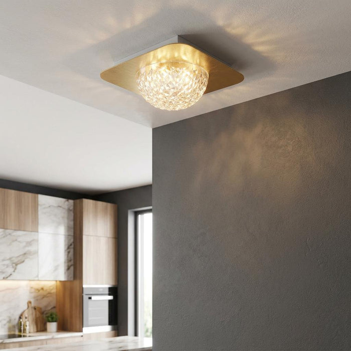 Square gold ceiling light with faceted acrylic dome casting glowing patterns in a modern kitchen.
