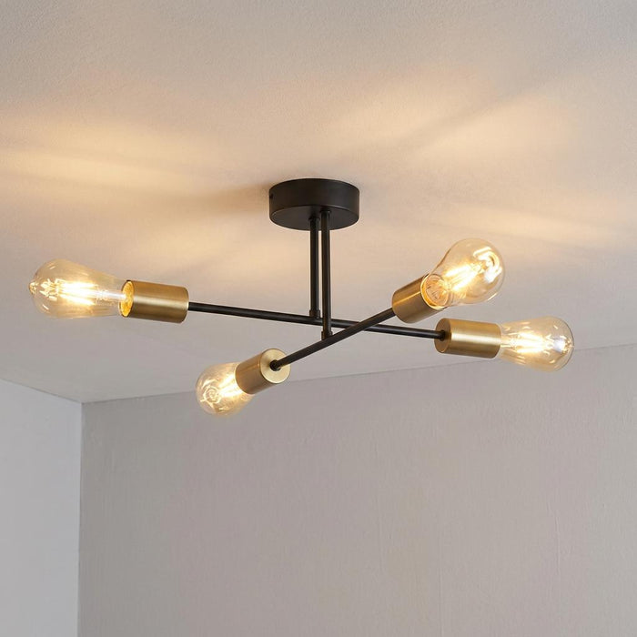 Chanin 4-light black and gold semi-flush ceiling fixture with exposed vintage bulbs glowing on a white ceiling.