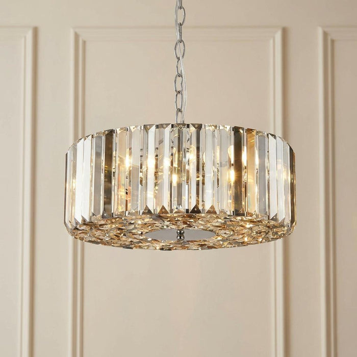 Chapeau chrome drum pendant with smoke and glass crystals glowing against a paneled wall.