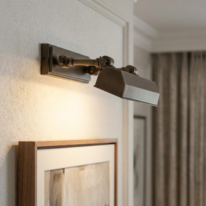 Chawton small dark bronze picture light mounted on a neutral wall illuminating a framed art piece.