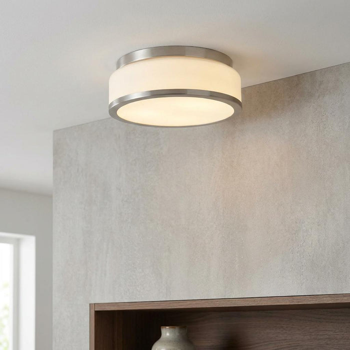 Satin silver flush mount ceiling light with an opal white glass shade illuminated in a modern interior.