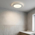Modern circular LED flush mount ceiling light with a white acrylic shade on a grey textured ceiling.