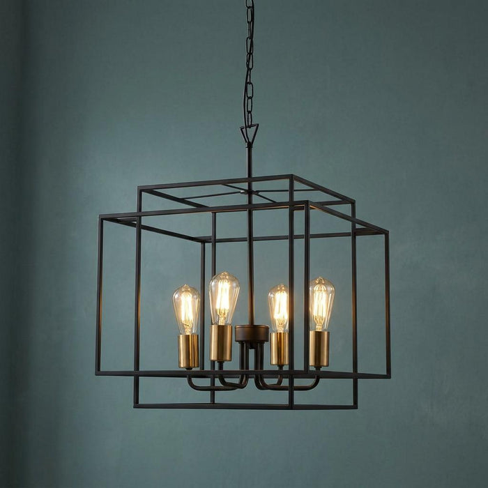 Geometric black frame pendant with four glowing bulbs and bronze lampholders against a dark teal wall.