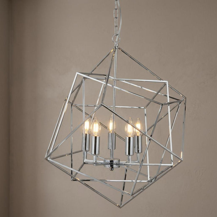 Modern chrome geometric cube pendant light with five lit bulbs against a neutral wall.