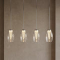 Four modern LED bar kitchen ceiling lights with clear glass shades and ribbed cones hanging against a neutral wall.