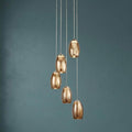 Cyclone 5-light LED multi-drop pendant with spiraled amber smoked glass shades hanging against a teal wall.