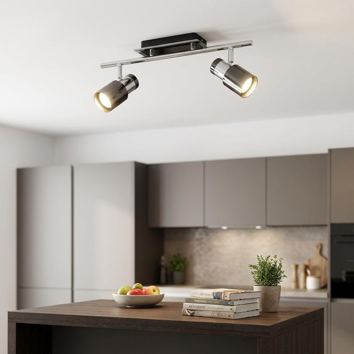 Modern black nickel and chrome 2-light bar spotlight mounted on a ceiling above a kitchen island.
