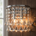 Dorchester chrome and crystal wall light with faceted drops, illuminated against a dark wood wall.