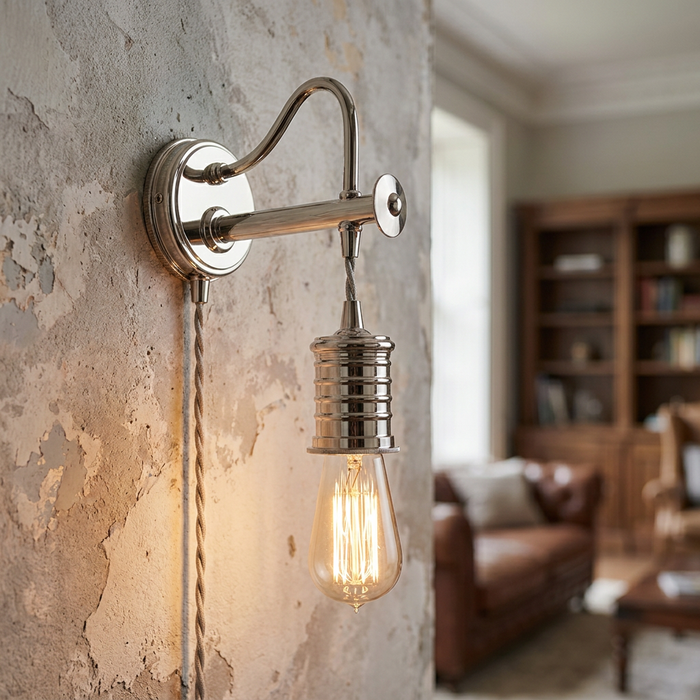 Polished nickel industrial wall light with an Edison bulb on a textured, distressed plaster wall.