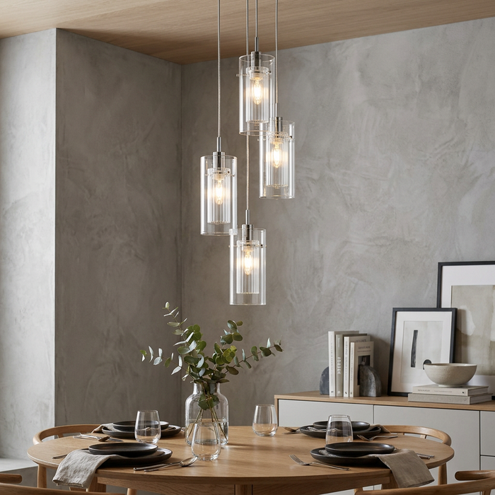 Chrome and double glass cylinder pendants hanging over a modern wooden dining table against a grey concrete wall.