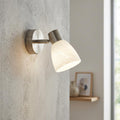 Eglo Dakar 1 wall spotlight with brushed nickel finish and white marbled glass shade on a textured wall.