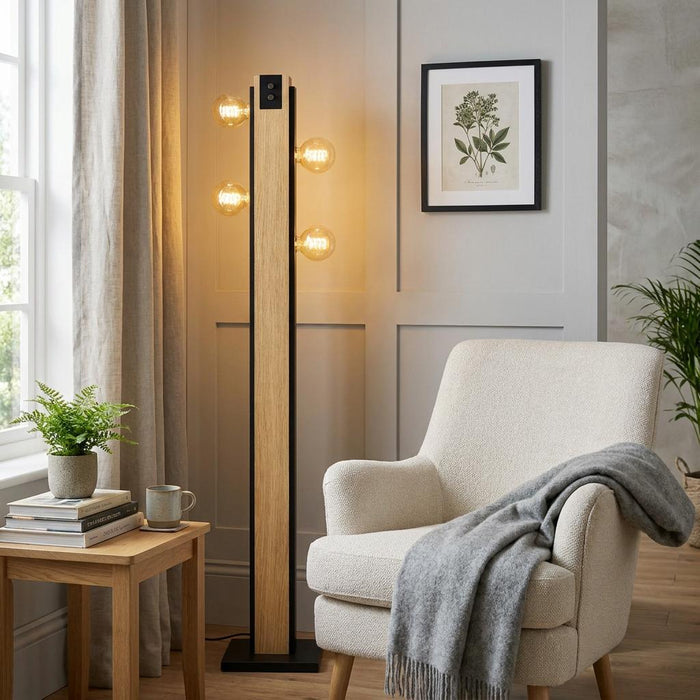 Modern Eglo Layham black and wooden floor lamp with four glowing bulbs next to a white armchair in a living room.